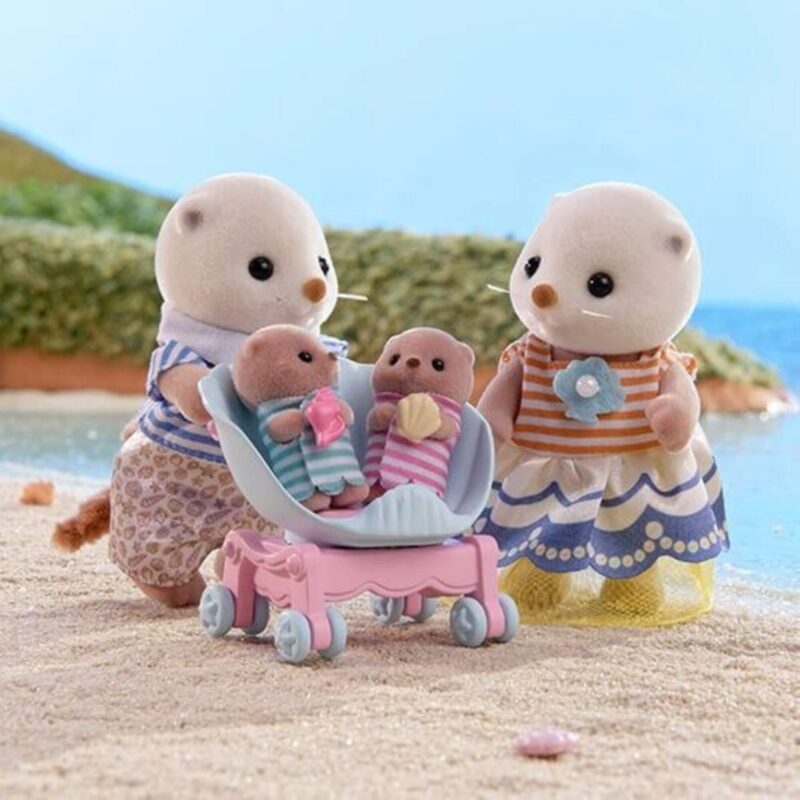 Close-up of Sylvanian Families Sea Otter parents with baby twins in a seashell stroller at the beach.