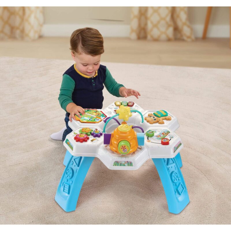 Toddler playing with the VTech Busy Bee Activity Table set up with legs in a living room setting.