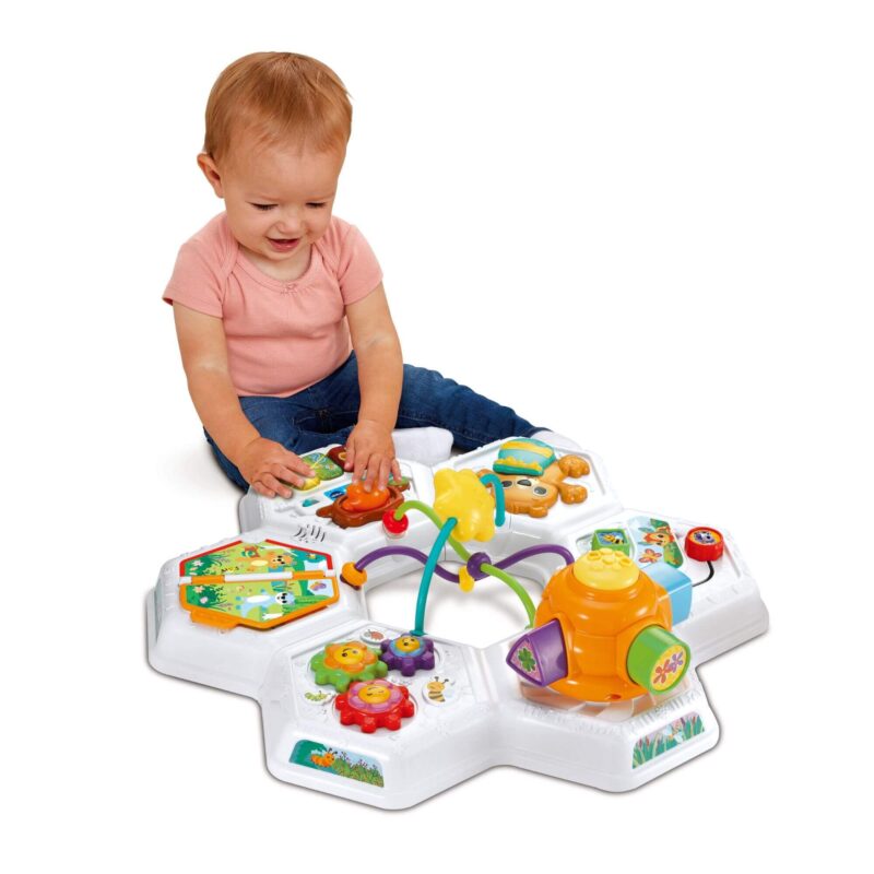 Baby sitting on the floor playing with the VTech Busy Bee Activity Table used without legs.