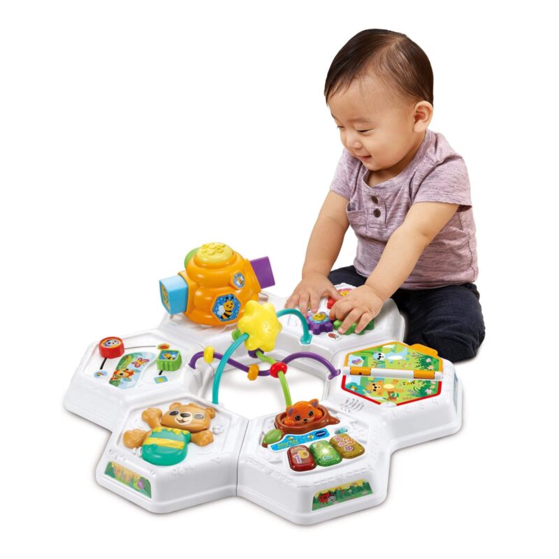 Toddler interacting with the VTech Busy Bee Activity Table placed directly on the floor without legs.