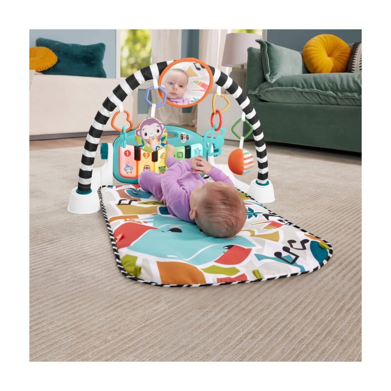 Baby lying and kicking piano keys on playmat