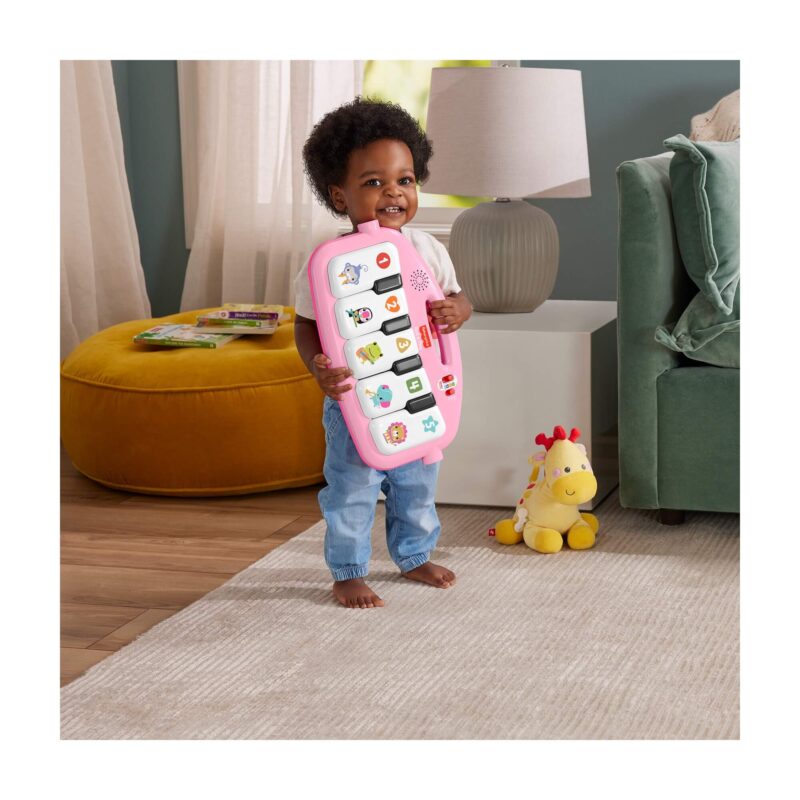 Toddler holding the removable pink piano