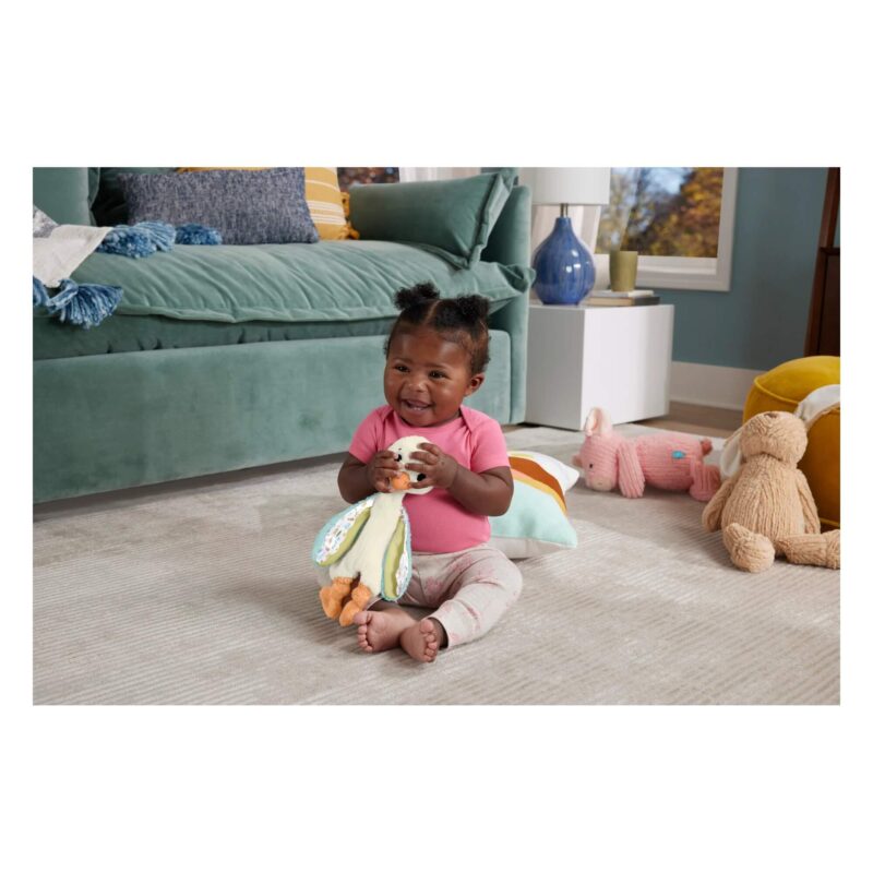 Smiling baby sitting and playing with goose toy
